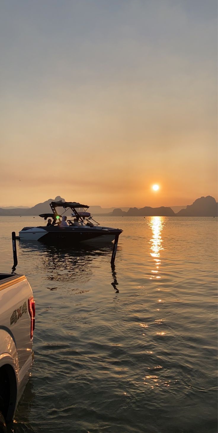 two boats are in the water at sunset