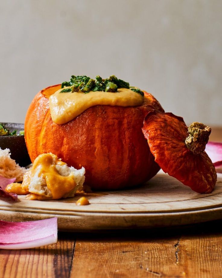 a wooden plate topped with an orange covered in sauce and other food items on top of it