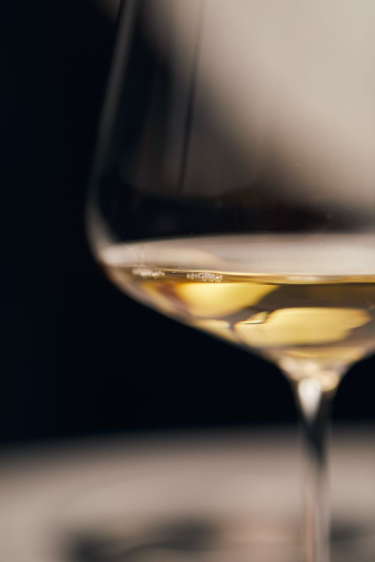 a wine glass filled with white wine on top of a table