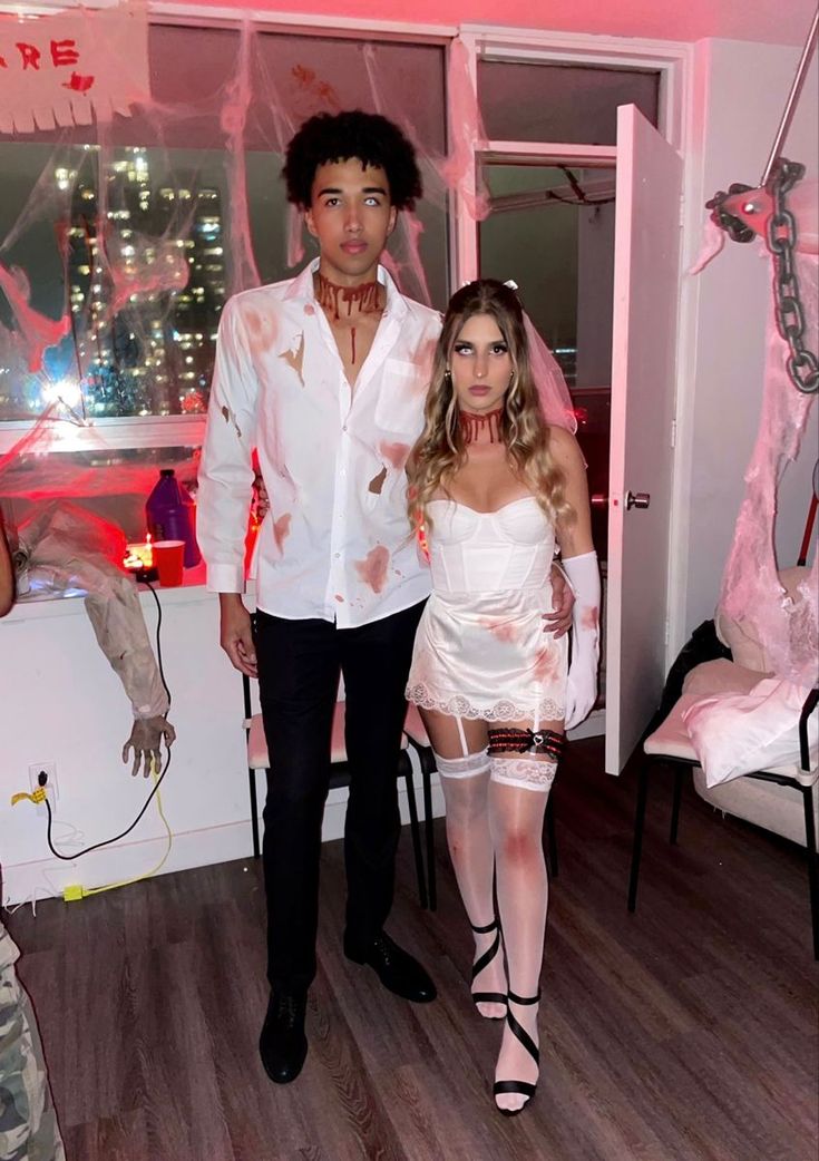 a man and woman dressed up as zombies in a room with pink paint on the walls