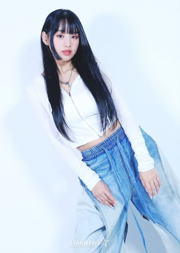 a woman with long black hair wearing blue jeans and a white shirt is posing for the camera