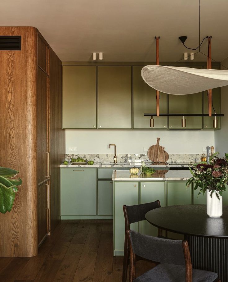 a kitchen with wooden floors and green cabinetry is seen in this image from the dining room