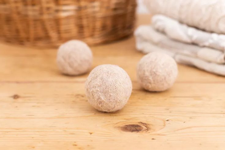 three balls of wool sitting on top of a wooden table next to towels and a basket