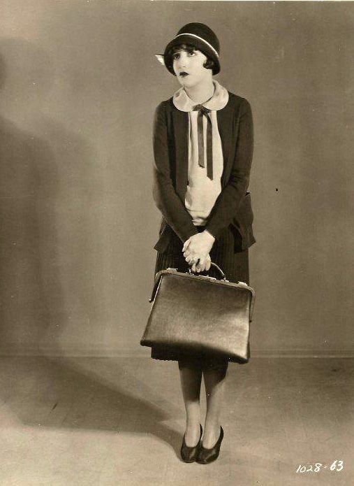 an old black and white photo of a woman with a purse in her hand,