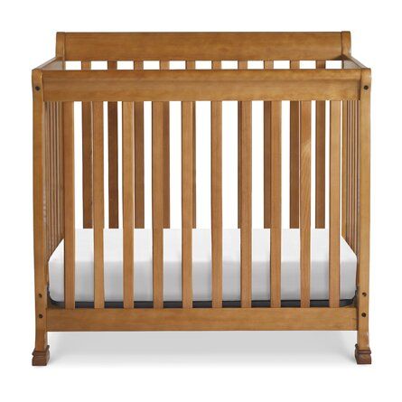 a wooden crib with white sheets on the bottom and side rails, against a white background