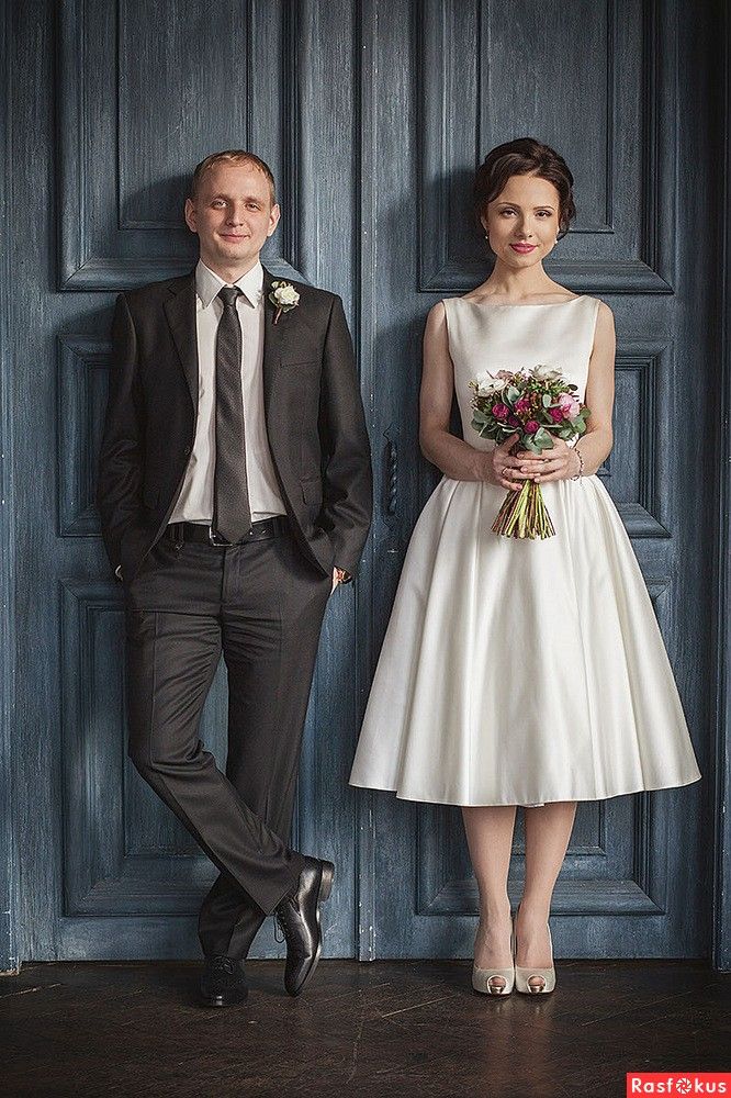 a man and woman standing next to each other in front of a blue wooden door