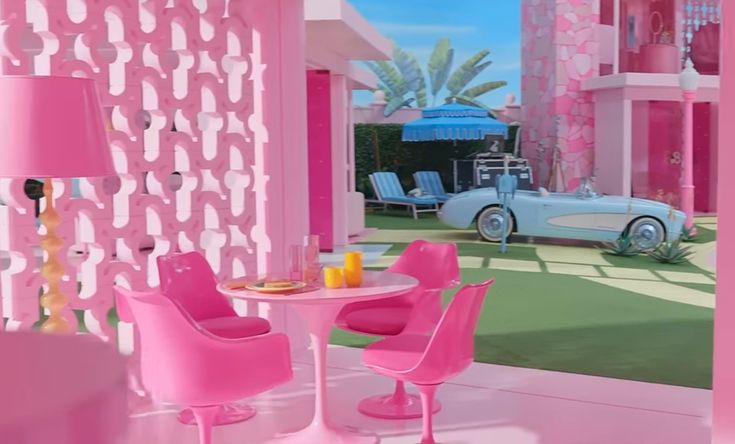 a pink room with two chairs, a table and a blue car in the background