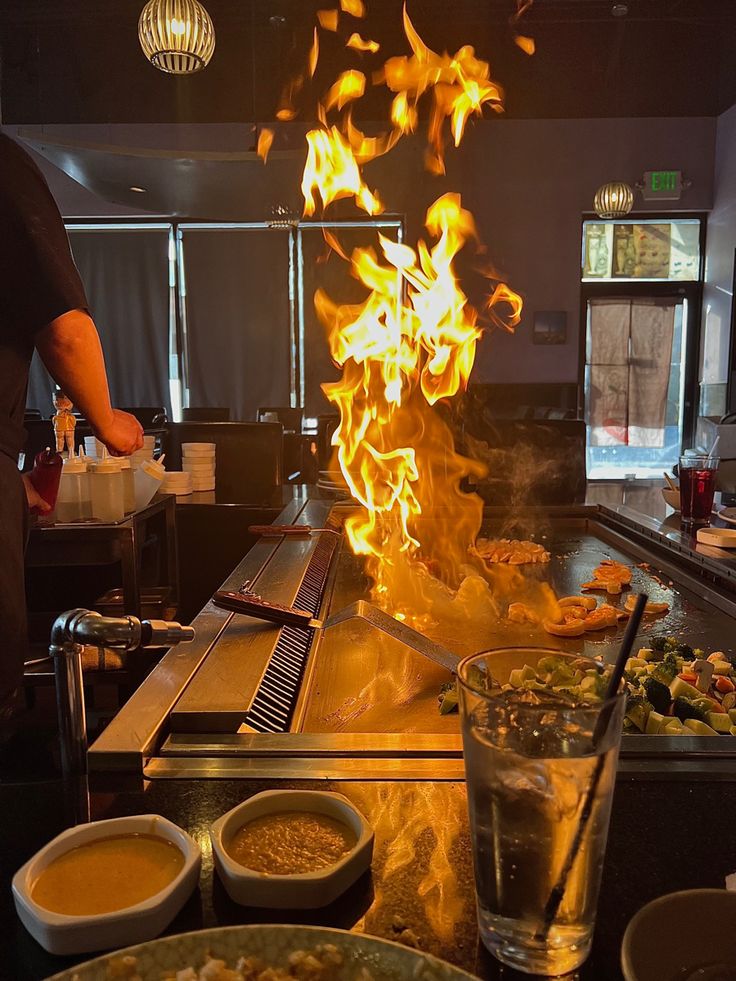 a man cooking food in a kitchen with flames coming out of the oven and on the counter