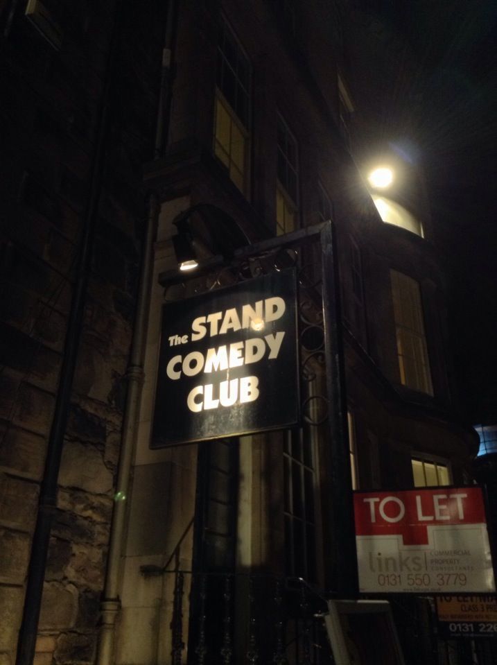 the stand comedy club sign is lit up at night