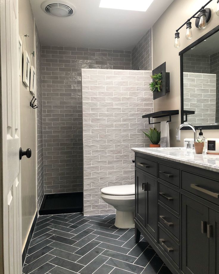 a white toilet sitting in a bathroom next to a walk in shower and tiled walls