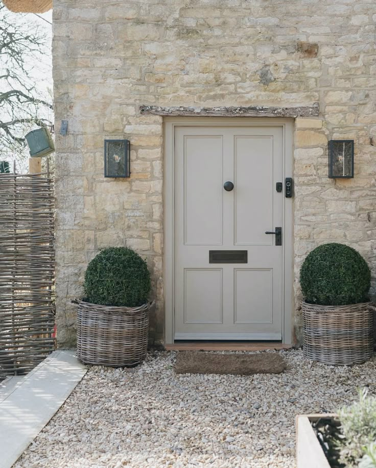 two planters sitting in front of a stone building with a white door and window