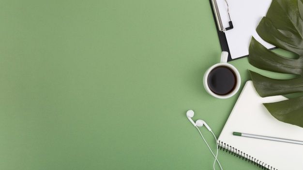 an overhead view of a desk with headphones, notebook and plant