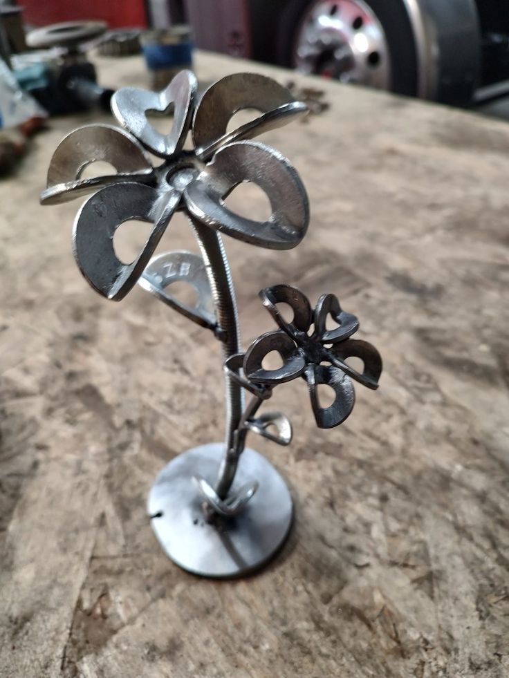 a metal flower sculpture sitting on top of a wooden table next to a red truck