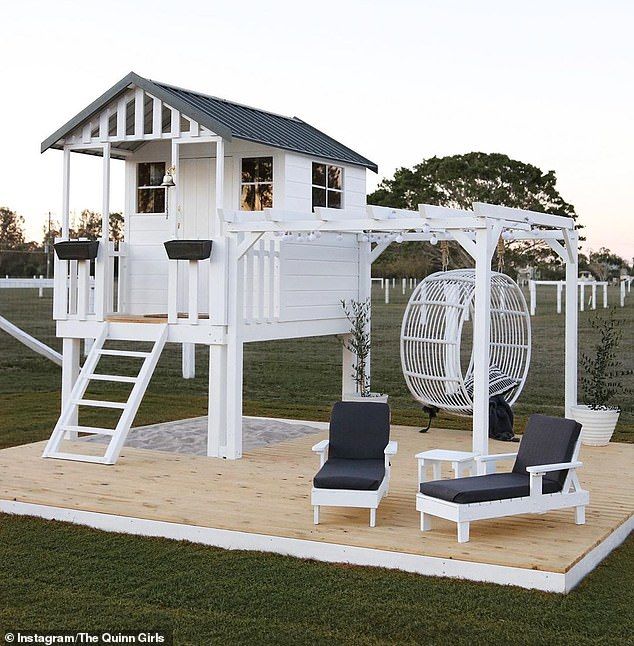 a white swing set sitting on top of a wooden platform