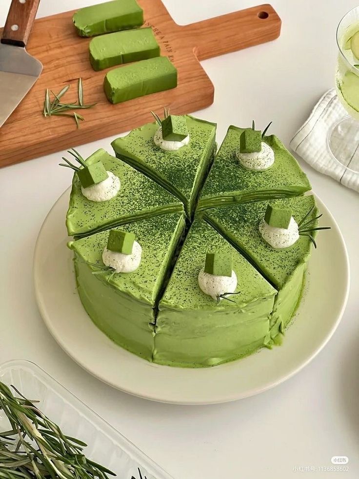 a green cake on a white plate with cucumber slices cut out and ready to be served