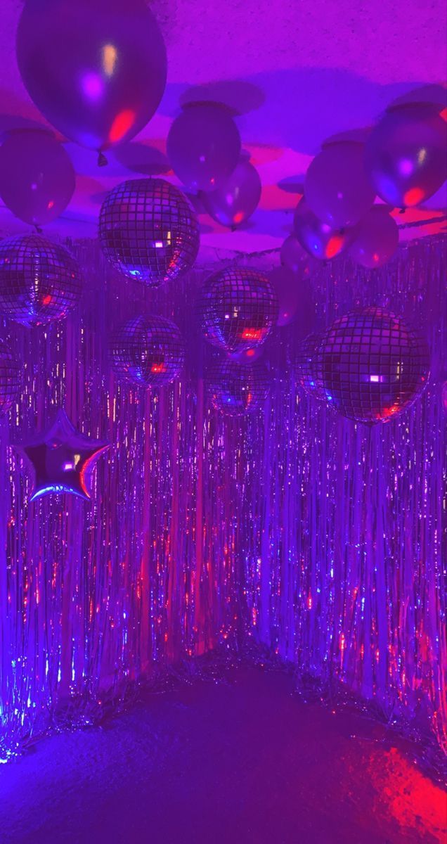 disco balls and streamers are hanging from the ceiling in this purple room with red lights