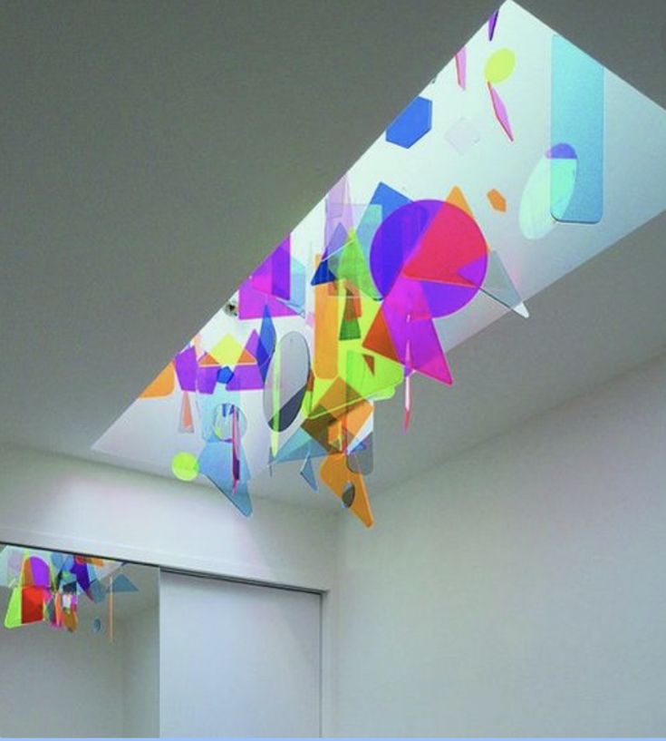 a room filled with white walls and colorful art hanging from the ceiling next to a doorway