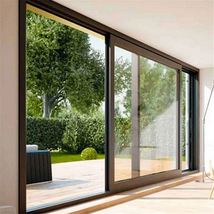 an empty room with sliding glass doors leading to a patio area and trees in the background