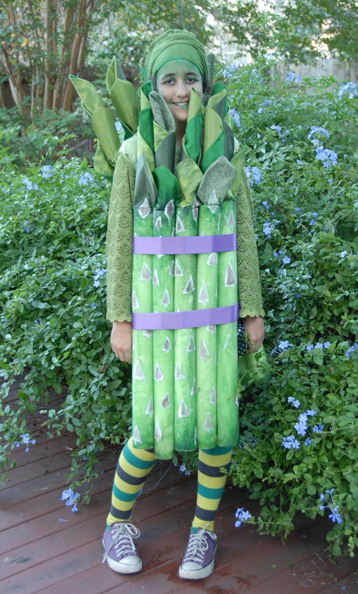 a person dressed in green and purple standing next to bushes