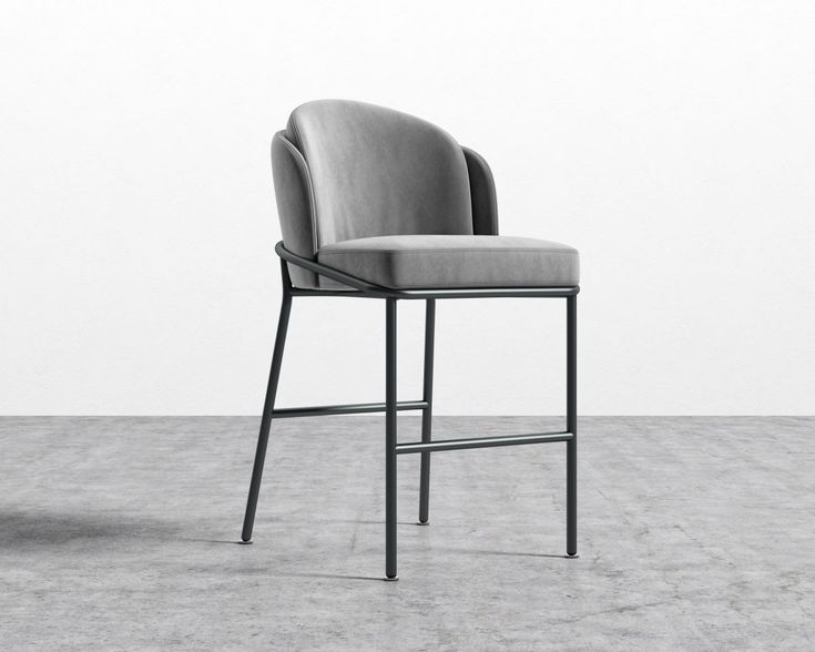 an upholstered chair sits in front of a white wall and grey concrete floor