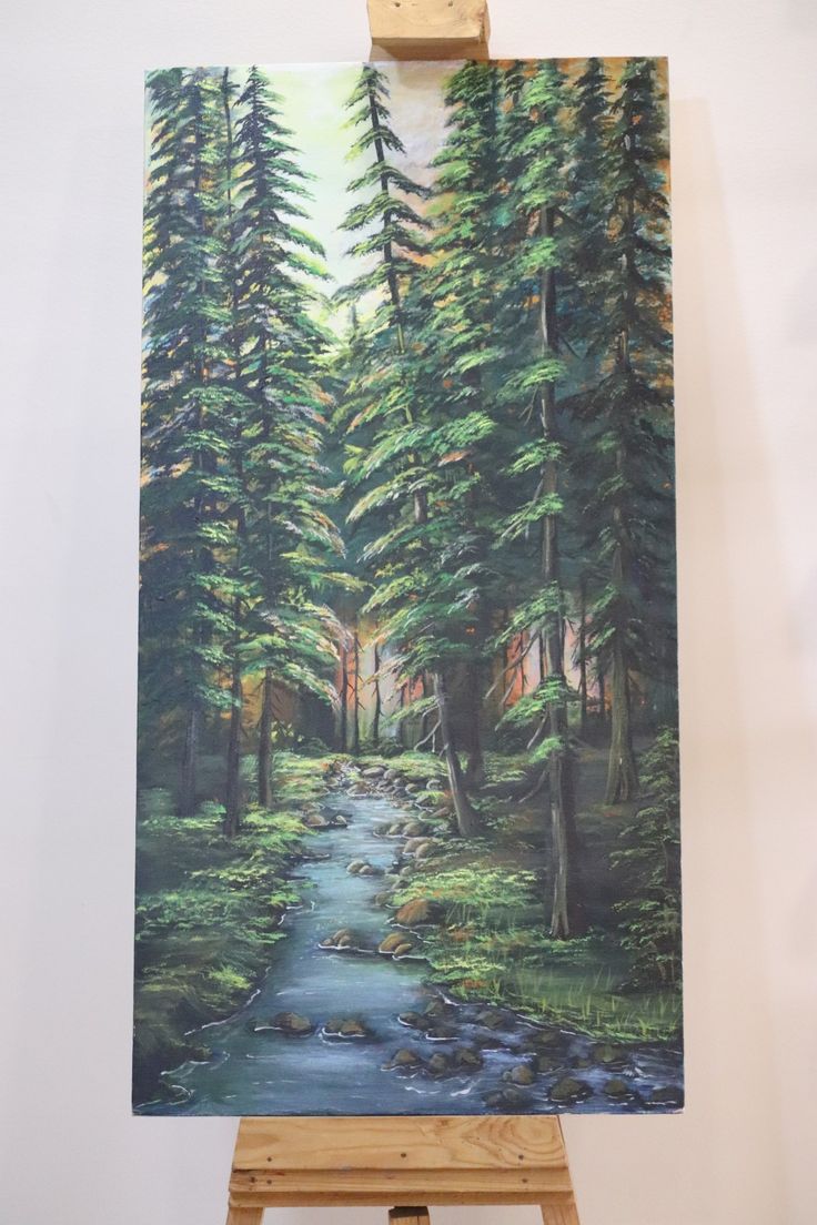 an easel holding up a painting of a forest scene with a stream running through it