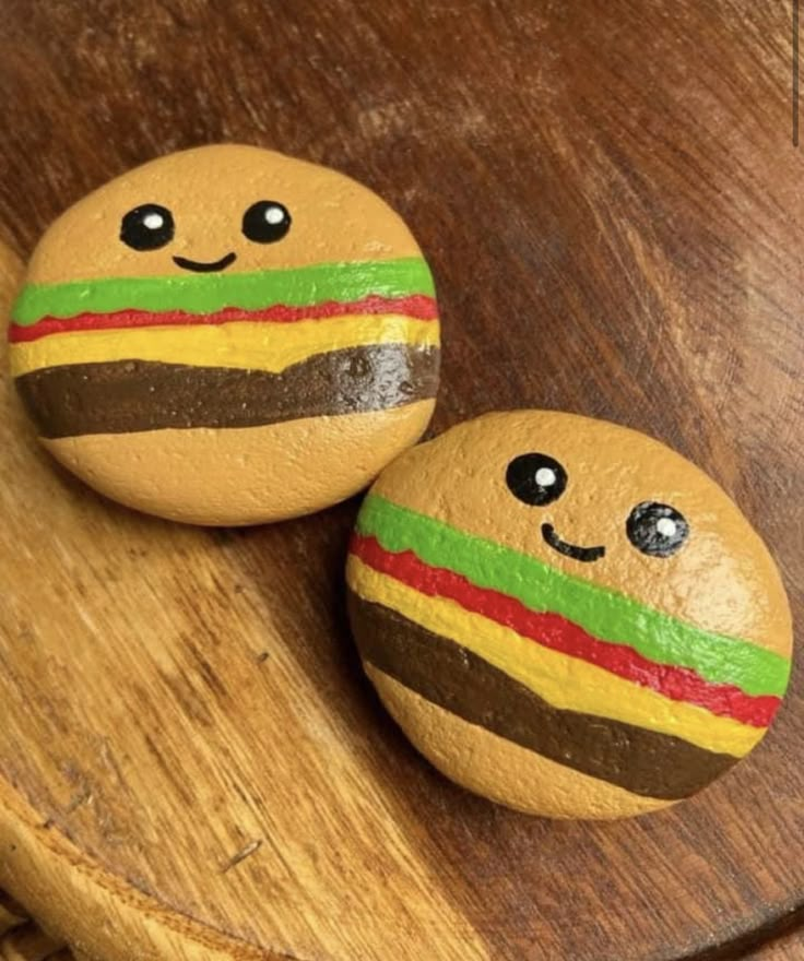 two painted rocks sitting on top of a wooden table