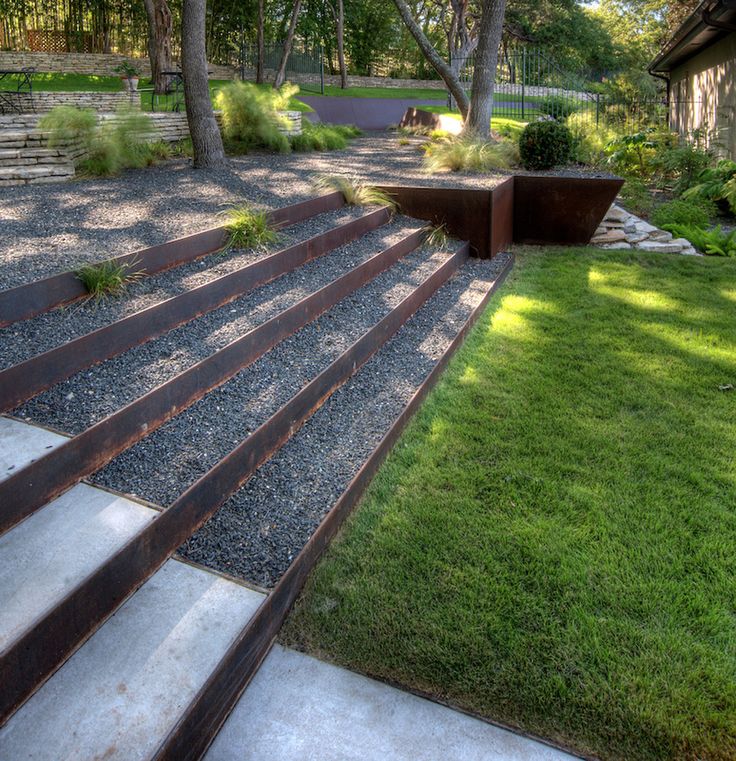 an outdoor garden with steps leading up to the lawn and trees in the back yard