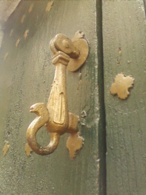 an old door handle on the side of a green wooden door with rusted metal handles