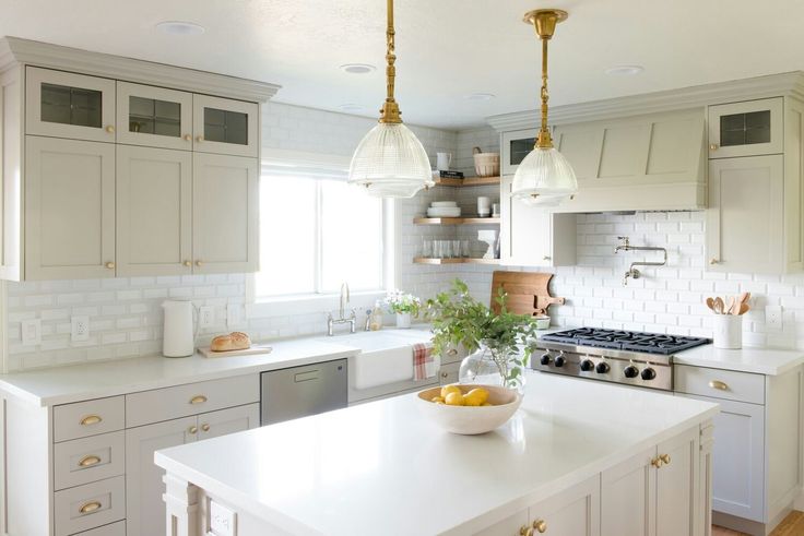 a kitchen with white cabinets and an island in front of the stove top is filled with fruit