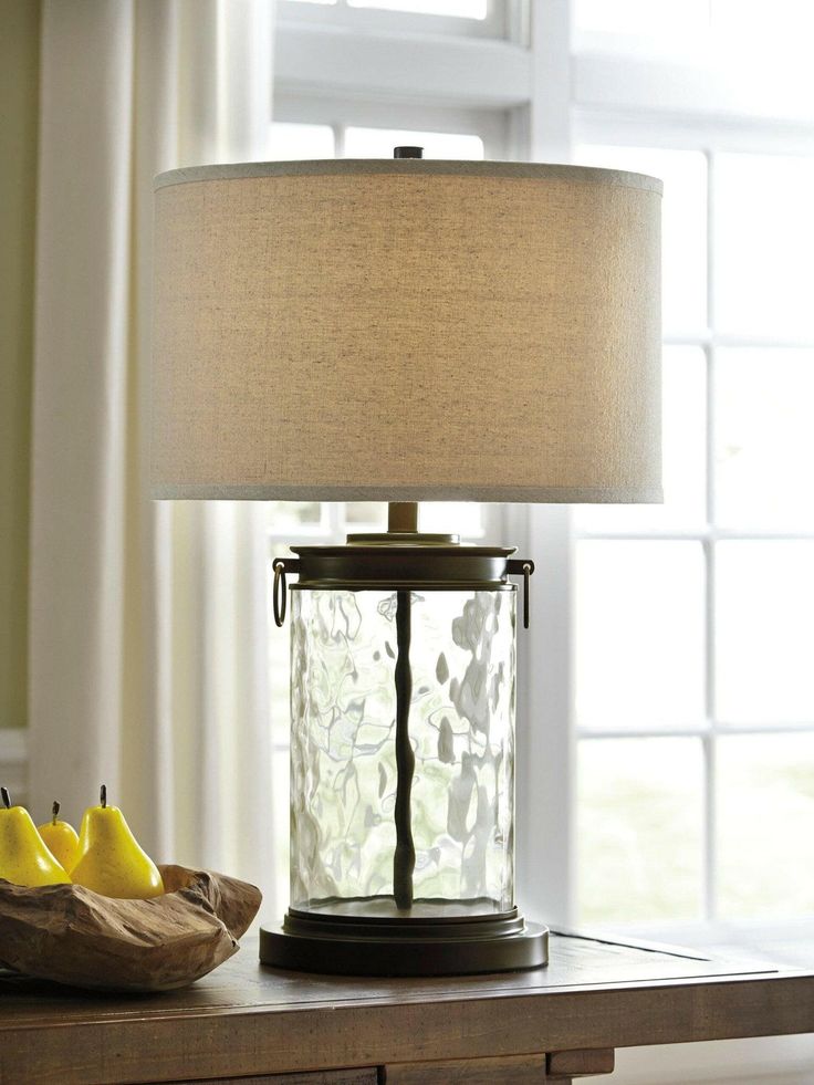 a table lamp sitting on top of a wooden table next to a basket of fruit