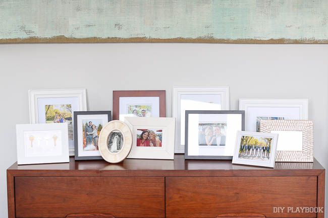 a dresser topped with lots of framed pictures