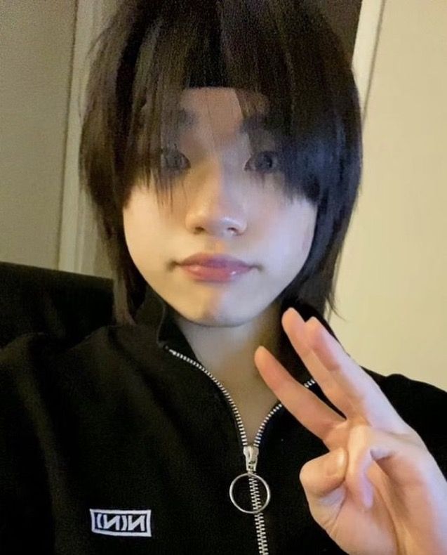 a young woman making the peace sign with her hand while wearing a black shirt and silver necklace