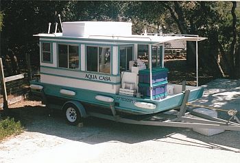 the small boat is parked on the side of the road in front of some trees