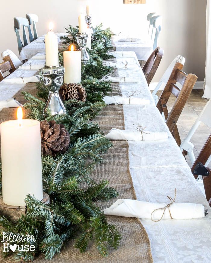 a long table with candles and pine cones on it is decorated for the holiday season