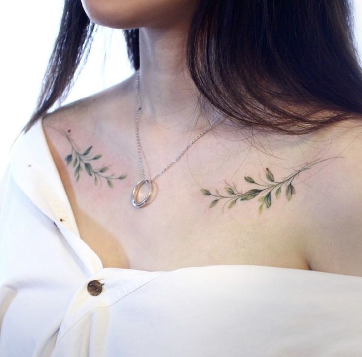 a woman wearing a white dress with green leaves on her chest and an oval necklace