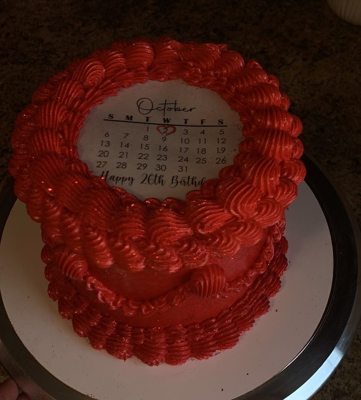 a red heart shaped cake sitting on top of a white plate next to a calendar