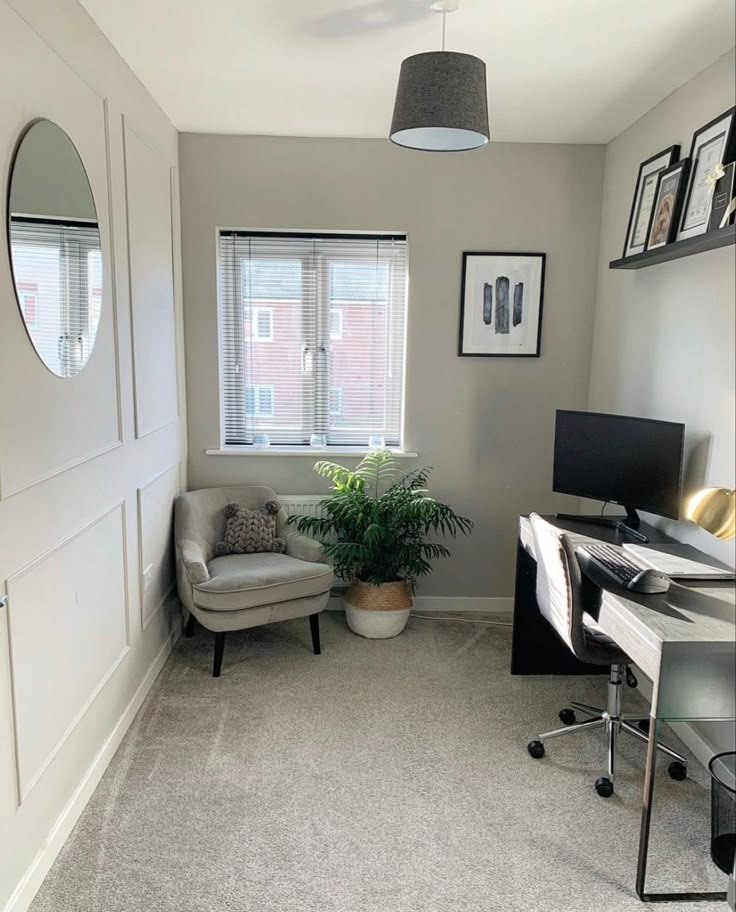 a living room with a chair, desk and computer on the floor in front of a window