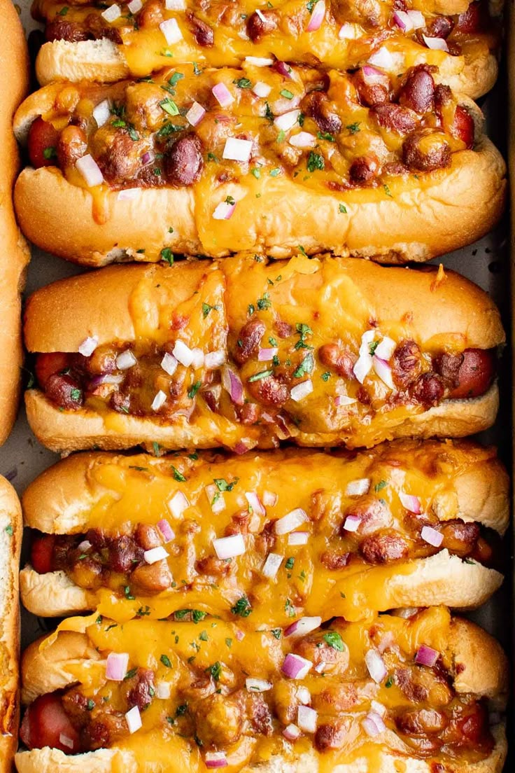 hot dogs with cheese, onions and ketchup are lined up in a pan