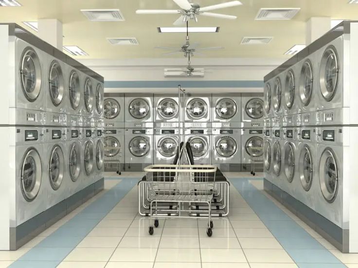 an empty laundry room with several washing machines in it and a shopping cart on the floor