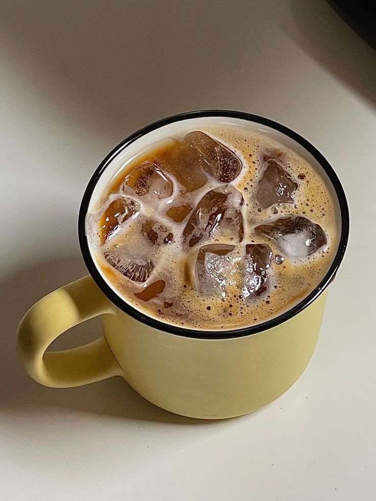 a yellow cup filled with ice on top of a table