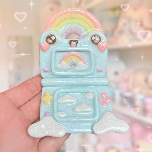 a hand holding a small toy oven with a rainbow on it's front and side