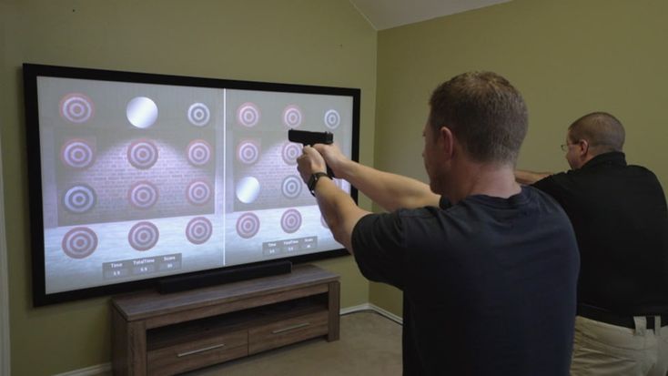 two men are playing a video game on the big screen tv in their living room