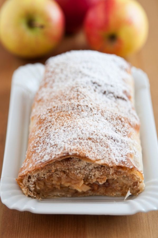 an apple pie on a white plate next to some apples