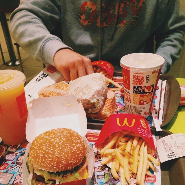 a person sitting at a table with two hamburgers and french fries