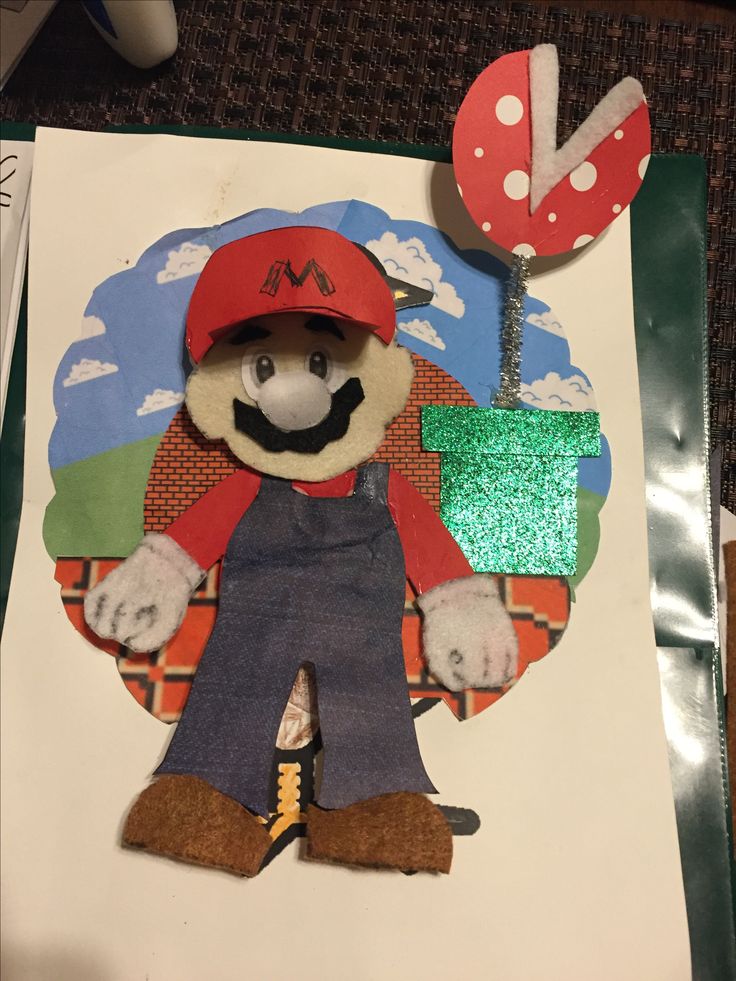 a paper cut out of mario with a red hat and blue overalls, standing next to a street sign