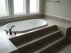 a bath tub sitting in the middle of a bathroom next to two windows and steps leading up to it