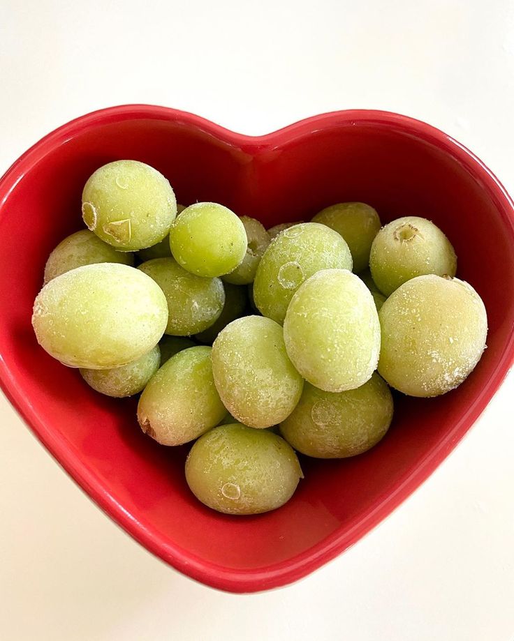 a heart shaped bowl filled with green grapes