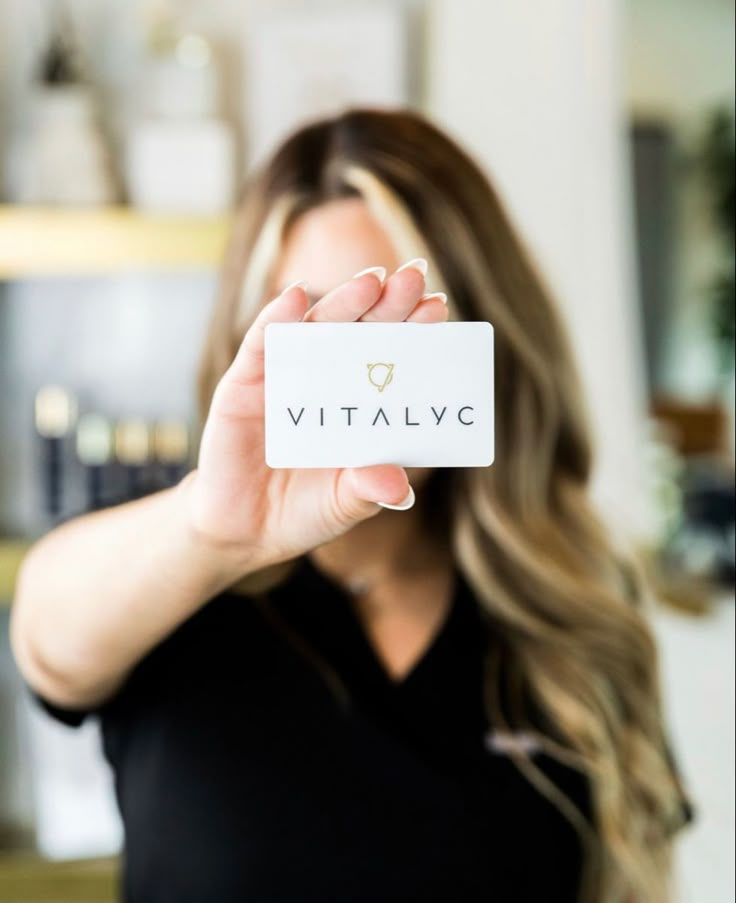 a woman holding up a business card with the word vitalve written on it