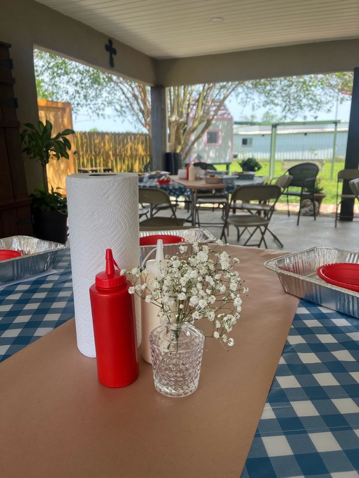 the table is covered with blue and white checkered tables cloths, vases filled with baby's breath flowers