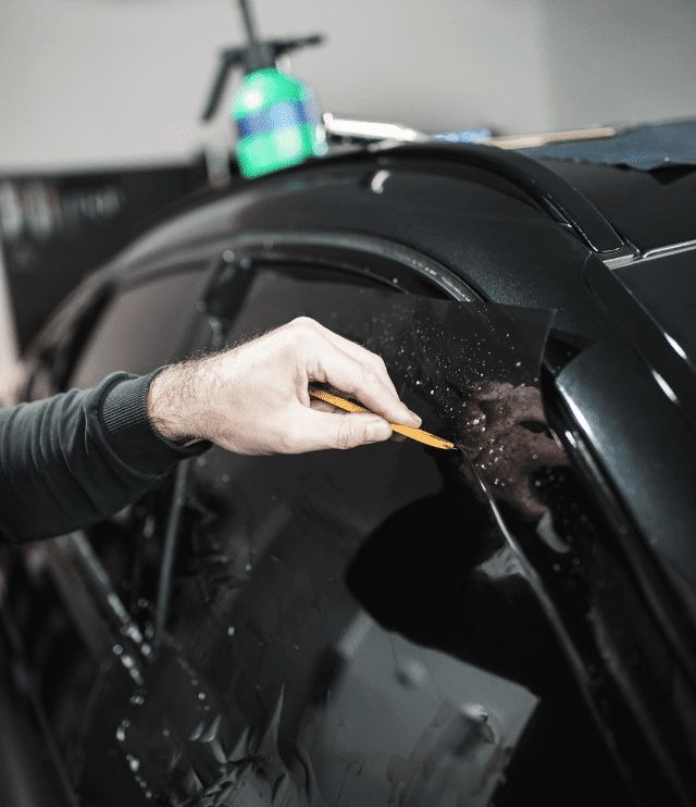 a man is painting the side of a car with black paint and yellow pencils